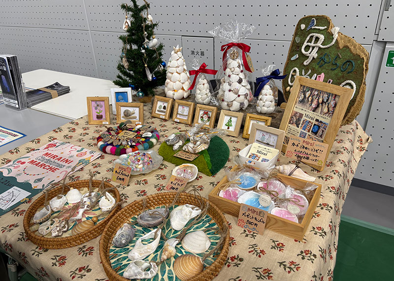 
										    流木や貝殻などで作られたクリスマスツリーやインテリアグッズがテーブルの並べられ、販売されています
										  